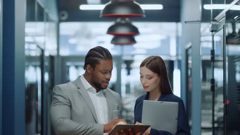 Multiracial-couple-getting-ready-for-meetup-in-office.-Colleagues-using-tablet