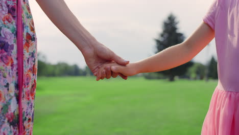 Unknown-woman-holding-girl-hand-outdoor.-Closeup-mother-and-daughter-hands.