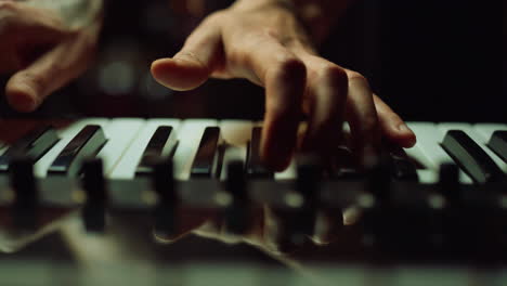 Musician-making-music-in-dark-hall-Man-hands-pressing-keys-on-piano-indoor.