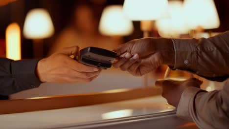 Waiter-hand-giving-bank-terminal-in-bar.-Man-making-contactless-payment-in-club