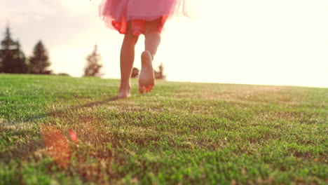 Unknown-girl-playing-in-city-park.-Rear-view-of-kid-legs-running-on-meadow.