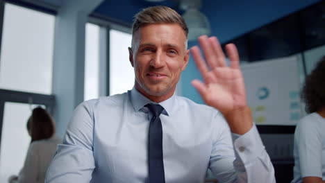 Portrait-of-positive-businessman-waving-hand-at-camera-during-online-video-call
