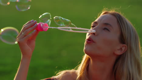 Portrait-of-young-mother-enjoying-sunset-in-park.-Tender-girl-blowing-bubbles.