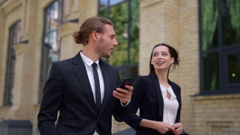 People-discussing-business.-Man-using-mobile-phone-on-way-to-work-with-colleague