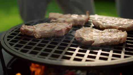 Big-meat-slices-browning-on-grate.-Juicy-meat-steaks-frying-on-grill-outdoors