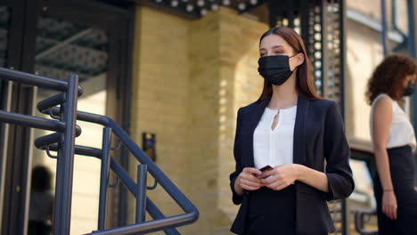 Mask-woman-meeting-with-masked-courier-outdoors.-Businesswoman-paying-card-order