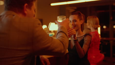 Cheerful-couple-spending-time-in-club.-Friends-clinking-glasses-in-bar