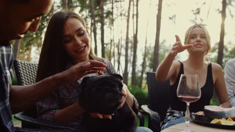 Happy-people-having-rest-on-grill-party-outside.-Smiling-woman-playing-with-dog