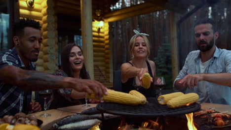Joyful-people-preparing-frying-corn-outside.-Fellows-putting-corn-on-bbq-grill