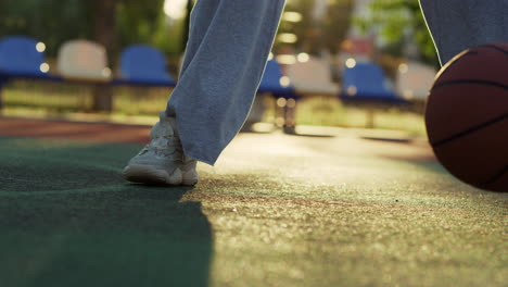 Closeup-focused-sporty-woman-playing-street-basketball-alone-in-playground.