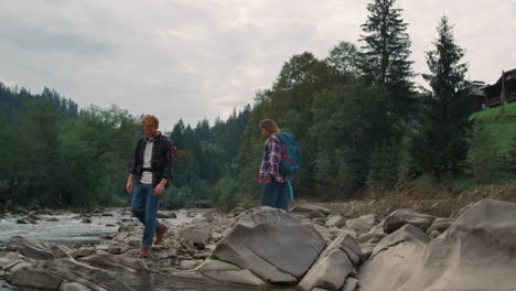 Man-and-woman-walking-on-rocks-at-river.-Couple-of-travelers-standing-at-river