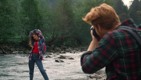Man-with-photo-camera-shooting-girl.-Woman-posing-at-camera-on-river-shore