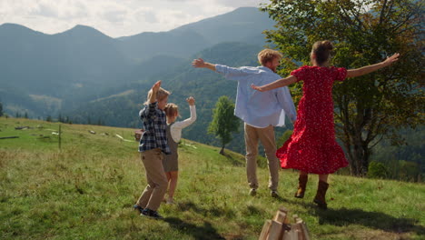 Family-jumping-raising-hands-up-on-green-hill.-Parents-having-fun-with-children.