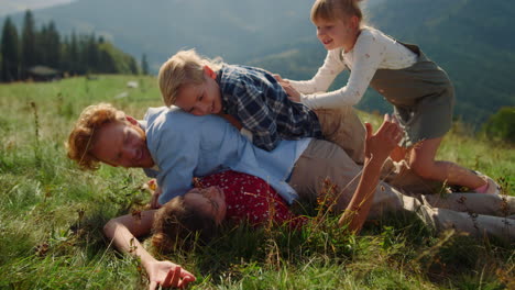 Family-piled-each-other-lying-green-grass-hill-close-up.-Happy-parents-playing.