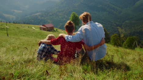 Family-hugging-sitting-green-grass-hill.-Parents-enjoying-nature-with-children.