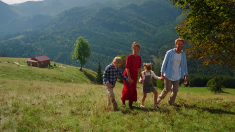 Carefree-family-walk-together-on-green-slope.-Parents-enjoying-nature-with-kids.