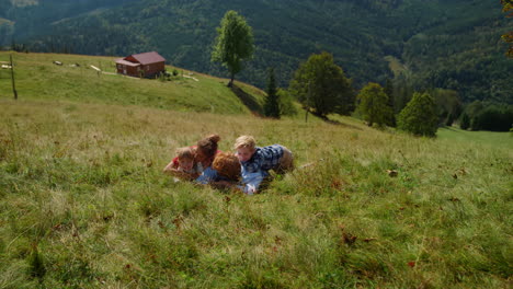 Family-rest-green-grass-mountain-meadow.-Joyful-parents-children-lying-ground.