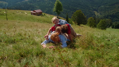 Happy-family-lying-piled-top-each-other-on-green-hill.-Couple-playing-with-kids.