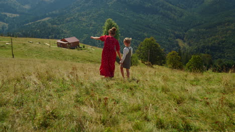 Unknown-woman-walking-daughter-on-green-hill.-Mother-and-child-enjoying-vacation
