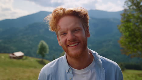 Portrait-happy-man-smiling-on-green-meadow.-Red-hair-guy-relaxing-on-vacation.
