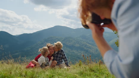 Hombre-Fotografiando-Mujeres-Niños-Frente-A-Las-Montañas.-Familia-Disfrutando-De-La-Sesión-De-Fotos.