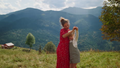 Mother-enjoy-funny-dancing-with-daughter-on-green-hill.-Family-summer-holiday.
