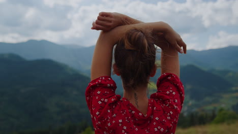 Back-view-woman-raising-hands-standing-in-front-beautiful-mountains-close-up.