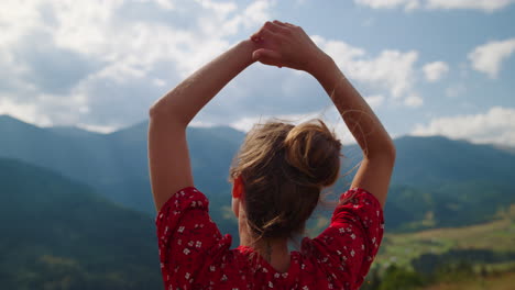 Woman-admiring-mountains-view-standing-on-hill-close-up.-Girl-raising-hands.