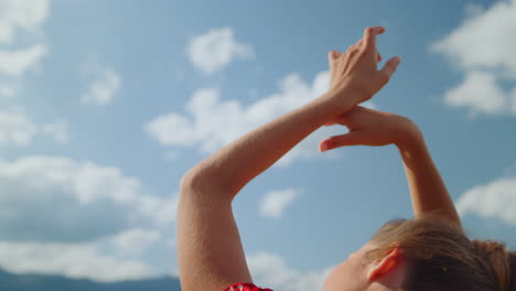 Closeup-woman-hands-cloudy-sky.-Back-view-carefree-girl-raising-arms-on-nature.