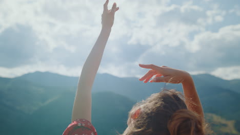 Girl-enjoy-sunlight-raising-hands-to-cloudy-sky-closeup.-Back-view-woman-outdoor