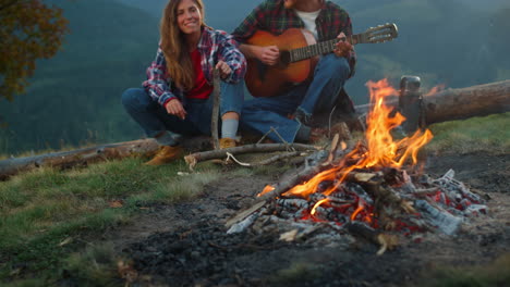Romantic-couple-camp-together-in-mountains-closeup.-Tourists-play-guitar-outside