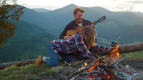 Camping-tourists-enjoy-picnic-on-mountains-hike.-Young-couple-relax-by-bonfire.