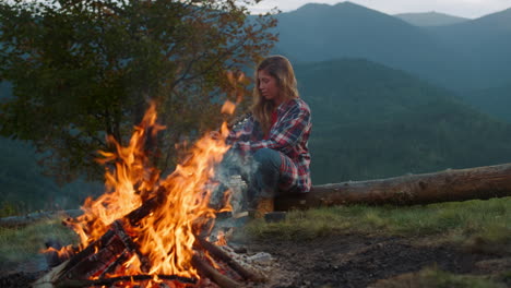 Active-woman-spend-evening-by-bonfire.-Young-hiker-play-guitar-in-mountains.