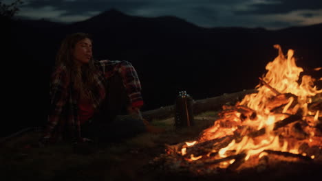 Lonely-woman-look-campfire-burn-on-dark-evening.-Hipster-tourist-relax-outside.