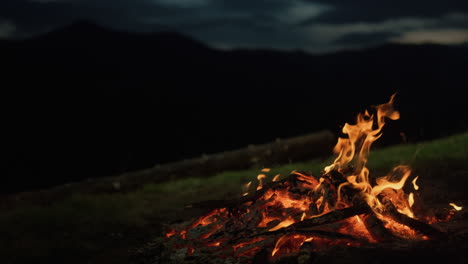 Closeup-camp-fire-burning-in-dark-evening-night-mountains-landscape-nature.