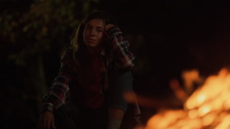 Adventurous-girl-enjoy-campfire-burning-on-dark-night-outdoors.-Travel-concept.