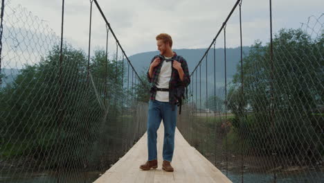 Excited-hiker-walk-mountains-on-river-bridge.-Smiling-man-travel-on-holiday-trip