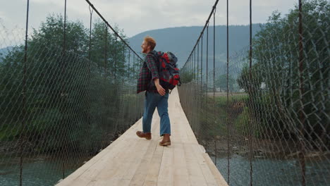 Happy-hiker-enjoy-traveling-in-mountains-forest.-Joyful-tourist-jump-on-bridge.