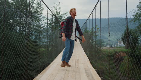 Energiegeladener-Mann,-Der-Berge-Auf-Einer-Naturwanderung-Erkundet.-Touristensprung-Auf-Flussbrücke
