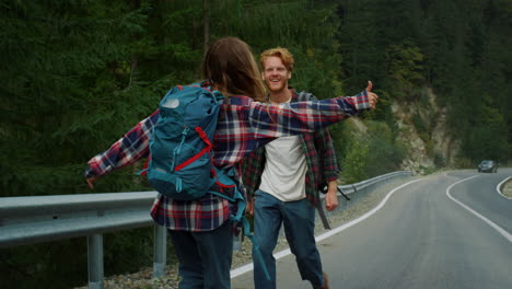 Two-backpackers-hitchhiking-road.-Couple-tourists-catch-wait-car-in-mountains.