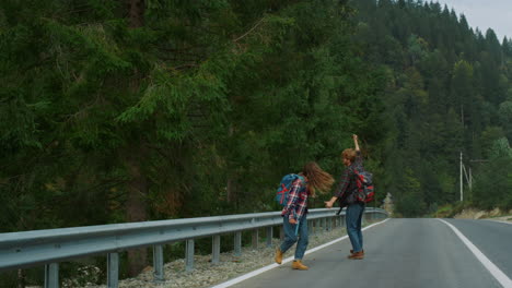Dancing-lovers-walk-hitchhike-on-forest-roadside.-Couple-hikers-jump-in-mountain