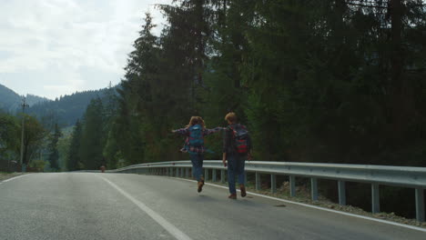 Friends-trekking-mountains-road-in-forest-nature.-Couple-wear-backpacks-outside.