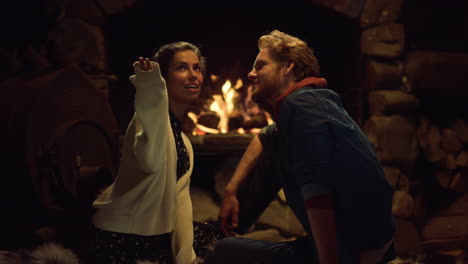 Boyfriend-girlfriend-sitting-fireplace-on-evening-date.-Couple-talk-together.