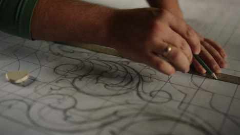 Man-hands-preparing-pattern-in-carpentry-workshop.-Guy-drawing-design-in-studio