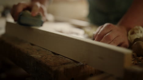 Craftmaster-preparing-wood-for-product-indoors.-Man-using-sandpaper-in-studio