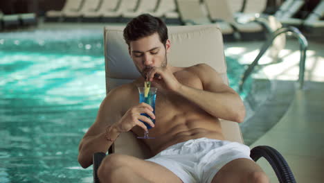 Closeup-man-drinking-cocktail-at-modern-spa.-Man-relaxing-with-cocktail-poolside