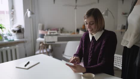 Junge-Frau-Sitzt-Zu-Hause-Am-Tisch-Und-Benutzt-Einen-Tablet-Computer