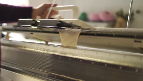 Female-hands-working-on-weaving-machine-in-workshop.-Knitting-woolen-fabric
