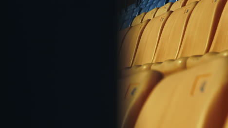 Leere-Gelbe-Und-Blaue-Sitze-Im-Fußballstadion.-Nahaufnahme-Einer-Reihe-Von-Plastikstühlen