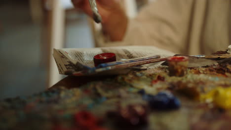 Creative-woman-mixing-paints-at-workplace.-Unknown-painter-using-brush-indoors.